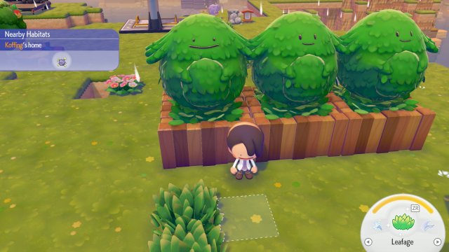 Trois arbustes à la forme d'un Pokémon souriant, plantés dans une jardinière en bois