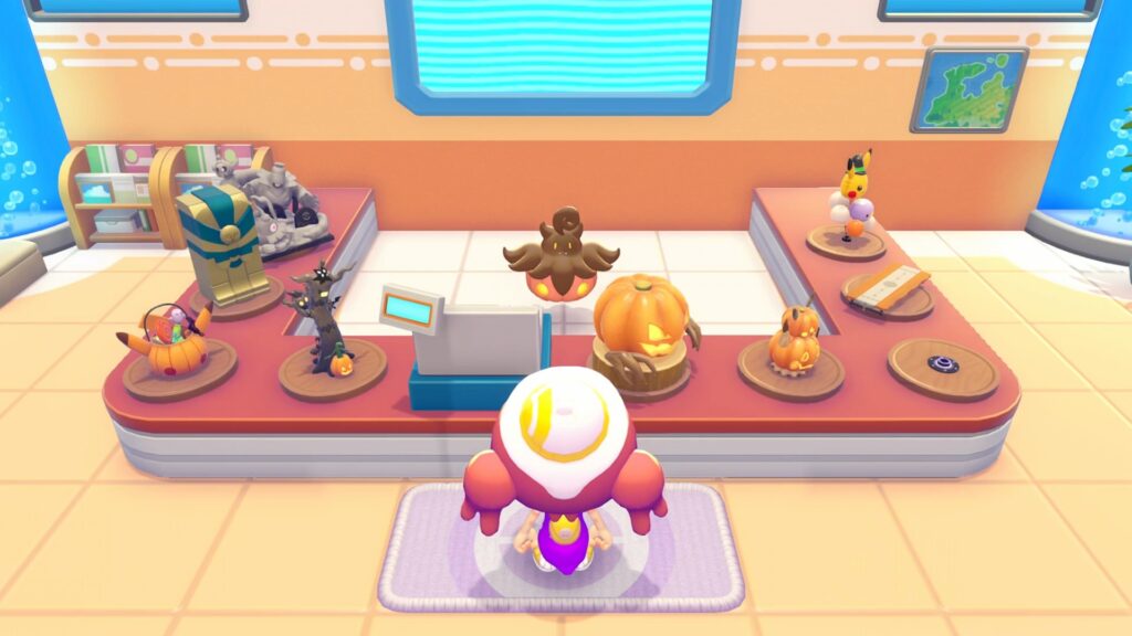 L'étal du Centre Pokémon avec les objets d'Halloween : sarcophage, statue, arbre hanté, citrouilles, panier et ballon Pikachu, avec Pitrouille au centre